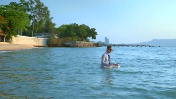 Homem de negócios feliz em um terno e óculos escuros está salpicando no mar em resorts de luxo. conceito de férias bem esperadas, freelancer . — Vídeo de Stock