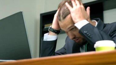 bir takım elbiseli bir adam bir dizüstü bilgisayarda ofiste bir masada çalışır ve tek kullanımlık bardak kahve içecek. Kopyalama alanı