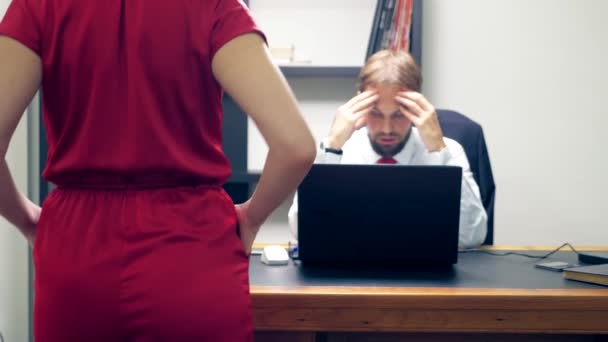 Office flirt. Attractive woman in red overalls with a deep neckline flirting at the table with her colleague. man looks at the chest of a woman in the office — Stock Video