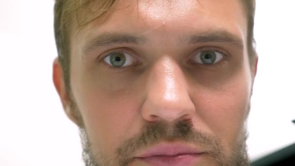 Close-up, green-eyed handsome man perplexedly looks into the camera — Stock Video