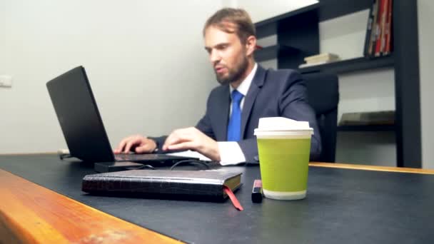 Un hombre que trabaja en un portátil en su oficina encuentra brillo labial dejado por alguien en su escritorio . — Vídeo de stock