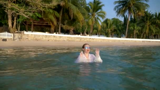 Mujer de negocios feliz en traje y gafas oscuras está salpicando en el mar en resorts de lujo. El concepto de unas vacaciones tan esperadas, freelancing . — Vídeo de stock