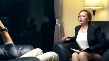 genel kavram-in müzakere, psikolojik danışmanlık. Bir kadın bir defter ile başarılı bir adam ile iletişim kurar. akşam bir deri sandalye ofisinde oturuyor.