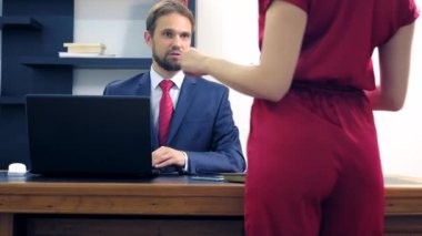 Ofis flört. Kırmızı tulum içinde çekici kadın iş arkadaşı ile masada flört derin bir yaka ile. Adam ofiste bir kadının göğsüne bakıyor