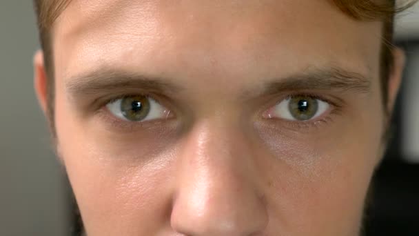 Gros plan, les yeux verts bel homme regarde perplexe dans la caméra — Video