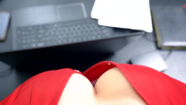 Bovenaanzicht, vrouwelijke borsten in focus. Aantrekkelijke vrouw in een rode blouse met een diepe halslijn, flirten op een bureau met haar collega. — Stockvideo
