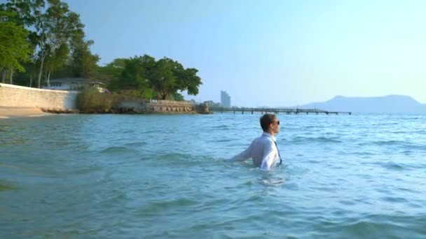 Happy zakenman in een pak en donkere glazen is spatten in de zee op luxe resorts. concept van de langverwachte vakantie, freelancen. — Stockvideo
