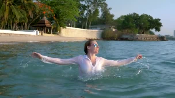 양복과 어두운 안경에 행복 한 비즈니스 여성이 럭셔리 리조트에서 바다에 튀는 것입니다. 대망의 휴가의 컨셉, 자유롭게. — 비디오