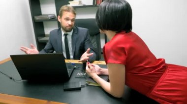 Ofis flört. Kırmızı tulum içinde çekici kadın iş arkadaşı ile masada flört derin bir yaka ile. Adam ofiste bir kadının göğsüne bakıyor