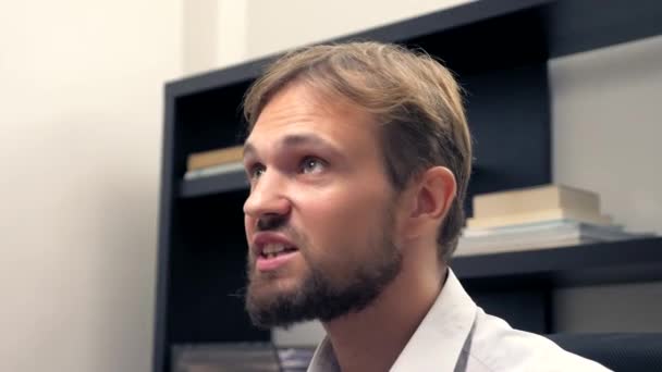 Раздражает человека с бородой, разговаривающего с кем-то в офисе — стоковое видео
