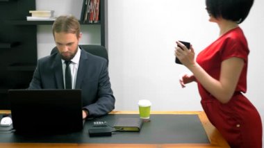 Ofis flört. Kırmızı tulum içinde çekici kadın iş arkadaşı ile masada flört derin bir yaka ile. Adam ofiste bir kadının göğsüne bakıyor