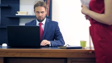 Ofis flört. Kırmızı tulum içinde çekici kadın iş arkadaşı ile masada flört derin bir yaka ile. Adam ofiste bir kadının göğsüne bakıyor