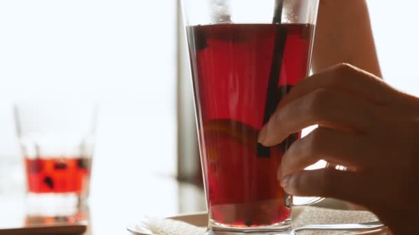 Primo piano. un bicchiere di vin brulé. le mani femminili mescolano la bevanda una paglia — Video Stock