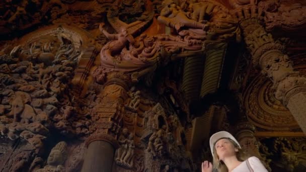 Woman tourist in helmet explores wooden buddhist temple inside — 비디오