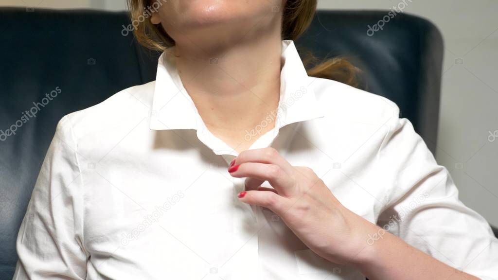 Business woman in a white blouse and with a red manicure unbuttoning his shirt, closeup
