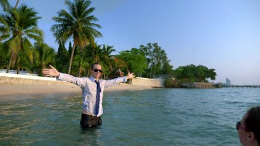 mutlu çift iş kadını ve işadamı takım elbise ve lüks tatil denizde içine sıçramasına güneş gözlüğü. Uzun zamandır beklenen tatil kavramı freelancing.