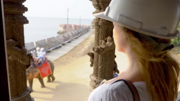 Woman tourist in helmet explores wooden buddhist temple inside — Stock Video