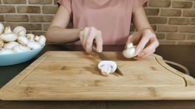 Mutfaktaki kadın, mantarları ahşap bir tahtada keser, yakın plan yapar.