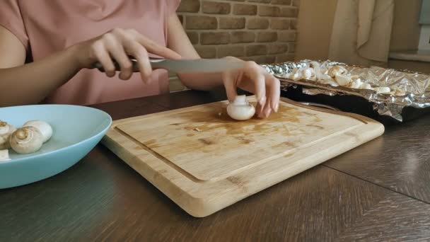 Woman at home in her kitchen cuts mushrooms on a wooden board, closeup — 비디오