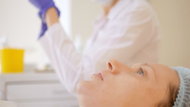 The beautician prepares a drug for injection, anti-aging procedures for tightening and smoothing wrinkles on the skin of the face and neck of a woman. — Stock Video