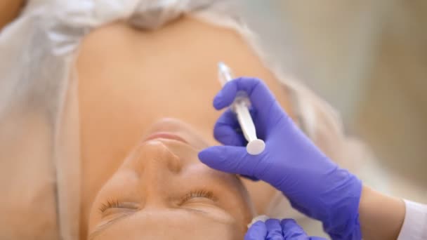 Kozmetolojist enjeksiyonlar yapar, bir kadının yüz ve boyun cilt kırışıklıkları sıkma ve yumuşatma için anti-aging prosedürleri. — Stok video