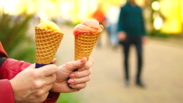 Qualcuno tiene il gelato alla frutta nei coni di wafer, primo piano. contro una strada pedonale sfocata in primavera o in estate — Video Stock
