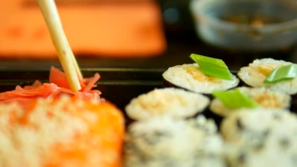 Nahaufnahme. jemand nimmt Sushi mit Stäbchen, Brötchen. — Stockvideo