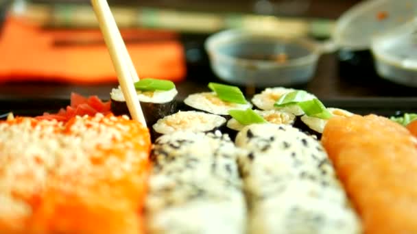 Γκρο πλαν. κάποιος παίρνει σούσι με ξυλάκια, ψωμάκια και ντιπ σε σάλτσα σόγιας — Αρχείο Βίντεο