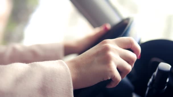 Las manos de las mujeres en un abrigo rosa en el volante del coche. mujer conduciendo un coche en primavera u otoño — Vídeo de stock