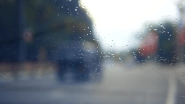 雨落在玻璃上。窗外的雨在路的背景上。雨中落在玻璃上的水滴. — 图库视频影像