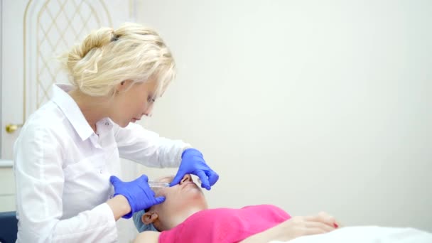 De cosmetoloog maakt injecties, Anti-Aging procedures voor het aanscherpen en gladmaken van rimpels op de huid van het gezicht en de nek van een vrouw. — Stockvideo