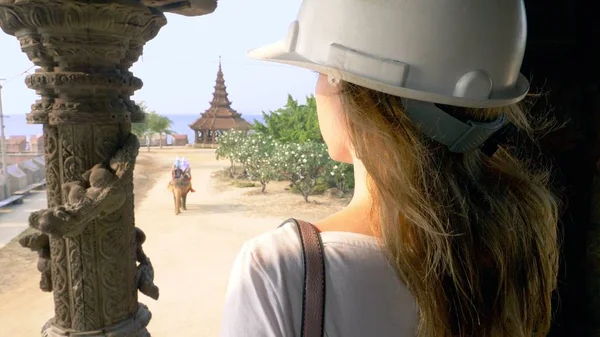 Turis wanita dalam helm menjelajahi kuil Buddha kayu di dalamnya — Stok Foto