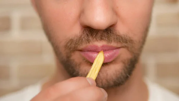 Primer plano. boca masculina. hombre comiendo papas fritas . —  Fotos de Stock