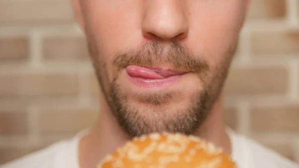 Usta zbliżenie. człowiek gryzie się kawałek Hamburger — Zdjęcie stockowe
