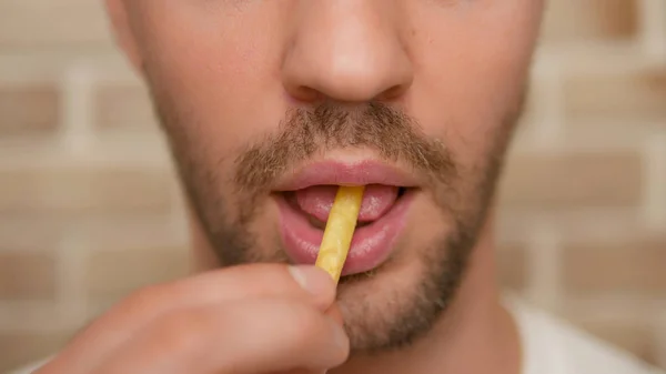 Primer plano. boca masculina. hombre comiendo papas fritas . —  Fotos de Stock
