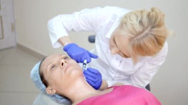 Kozmetolojist enjeksiyonlar yapar, bir kadının yüz ve boyun cilt kırışıklıkları sıkma ve yumuşatma için anti-aging prosedürleri.