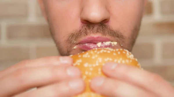 Boca de cerca. hombre muerde un pedazo de hamburguesa —  Fotos de Stock