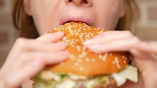 Primer plano de boca femenina. mujer muerde una hamburguesa — Foto de Stock