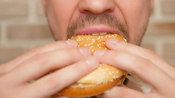 Boca de cerca. hombre muerde un pedazo de hamburguesa —  Fotos de Stock