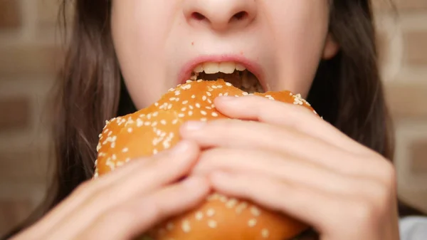 Nära. barnets mun. flicka äter en hamburgare — Stockfoto