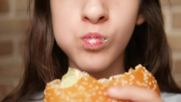 Cerca. boca de niño. chica comiendo una hamburguesa —  Fotos de Stock