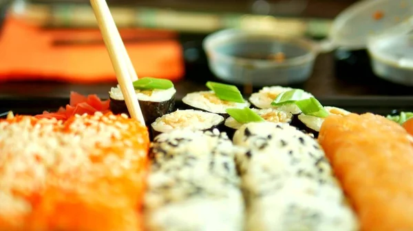 Close-up. iemand neemt Sushi met stokjes, broodjes en dips in sojasaus — Stockfoto