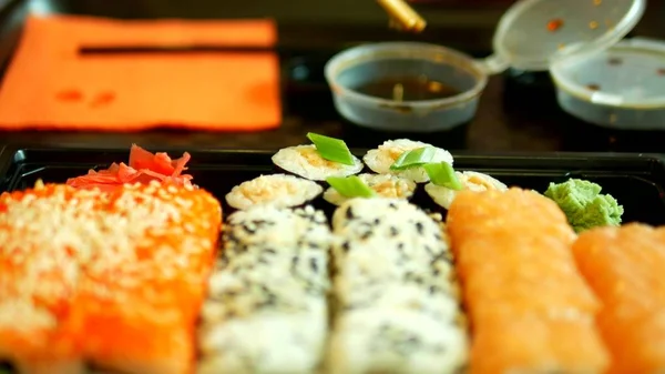 Close-up. někdo si vezme sushi s hůlky, rolky. — Stock fotografie