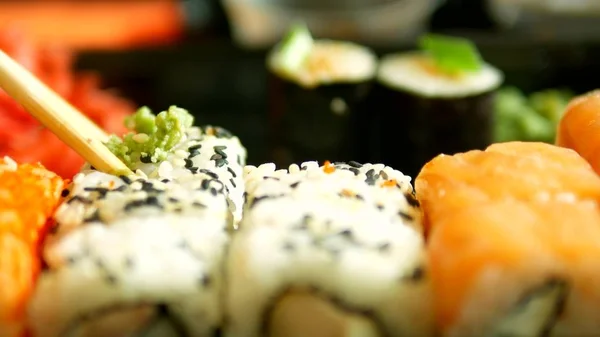 Close-up. iemand neemt Sushi met eetstokjes, broodjes. — Stockfoto