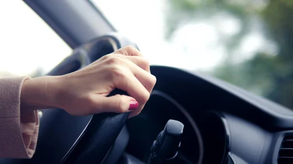 Mani delle donne in un cappotto rosa sul volante della vettura. donna alla guida di una macchina in primavera o in autunno — Foto Stock