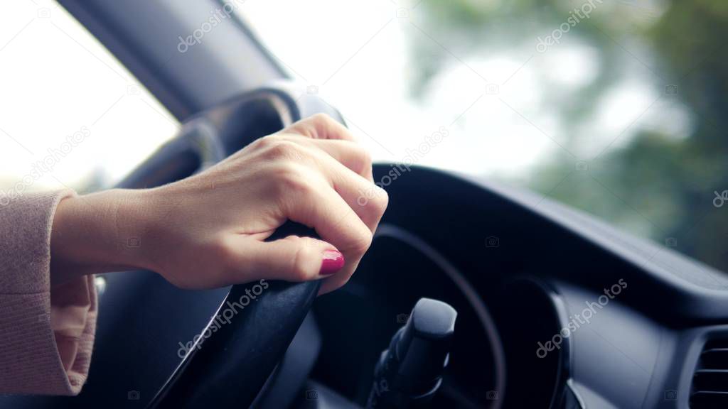 Womens hands in a pink coat on the steering wheel of the car. woman driving a car in spring or autumn