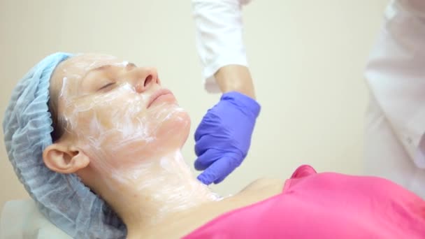 El concepto de esteticista. esteticista pone la crema en la cara de las niñas — Vídeo de stock