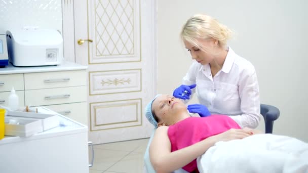 Kozmetolojist enjeksiyonlar yapar, bir kadının yüz ve boyun cilt kırışıklıkları sıkma ve yumuşatma için anti-aging prosedürleri. — Stok video