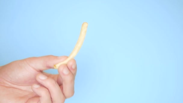 Mão masculina com batatas fritas no fundo azul — Vídeo de Stock