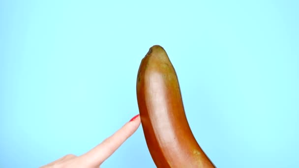 Kobiece ręce z czerwonym manicure dotknąć czerwonego Banana na niebieskim tle — Wideo stockowe
